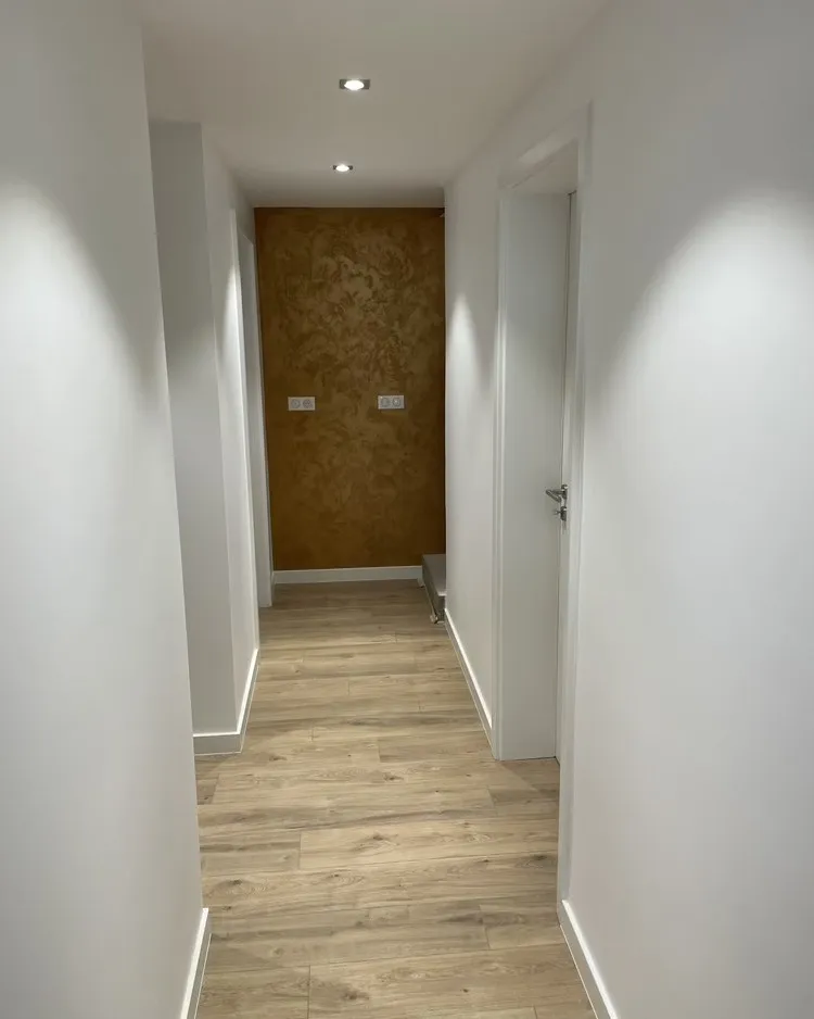 Couloir repeint en blanc, porte du fond habillée d'un enduit cuivré