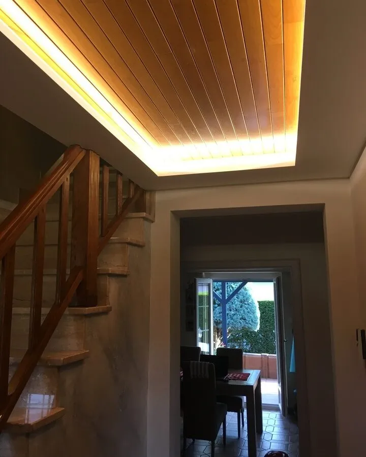 Faux plafond en lambris bois éclairé par un bandeau lumineux au-dessus d'un escalier